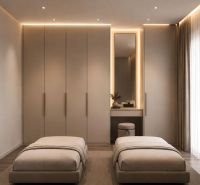 Pokoj rekreačního apartmánu s velkými skříněmi, dvěma postelemi a elegantním osvětlením.