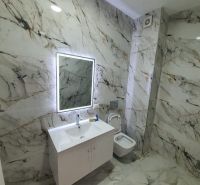 Koupelna v Rekreačním apartmánu s mramorovým dekorem a zrcadlem s LED podsvícením.