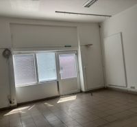 Interiér obchodních prostor s velkými okny a podlahou z dlaždic.