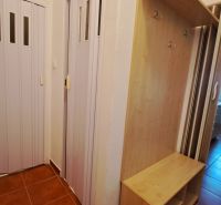 Vstup s hnědou dlažbou, šatníkovou skříní a posuvnými dveřmi v 2-pokojovém bytě.
