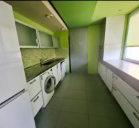 Kuchyně v 3-pokojovém bytě s pračkou, bílým nábytkem a zelenými stěnami.