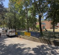 Ulice Líščie údolie v Bratislavě - Karlově Vsi se stromy a oploceným hřištěm.