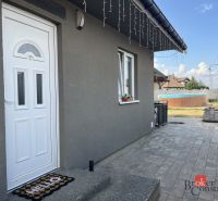 Rodinný dům na ulici SNP v Čani má šedou fasádu a upravenou zahradu s bazénem.