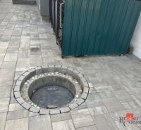 Podél betonové dlažby rodinného domu na SNP v Čani je kruhový poklop.