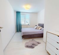 Světlá ložnice s podlahou s dřevěným dekorem, dvoulůžkem a bílou komodou ve 3-pokojovém bytě.