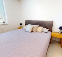 Ložnice s velkou postelí, nočními stolky a dekorativními polštáři ve 3pokojovém bytě.