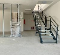 Interiér se schodištěm ve skladech a halách s kovovým zábradlím a nosníkem.