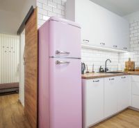 Kuchyně v 2-pokojovém bytě s retro růžovou lednicí a podlahou s dřevěným dekorem.