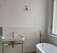 Koupelna s vanou a umyvadlem v rodinném domě s jednoduchým designem.