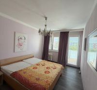 Ložnice s manželskou postelí, světlými stěnami a podlahou s dřevěným dekorem v 3-pokojovém bytě.