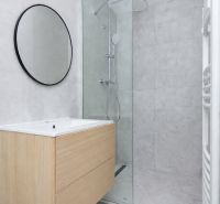 Koupelna ve 3-pokojovém bytě s moderním sprchovým koutem a dřevěným dekorem na skříňce.