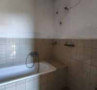 Koupelna v rodinném domě s vanou obloženou světlými obkladačkami.