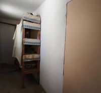 Úzká chodba s policemi v rodinném domě, jednoduché zařízení.
