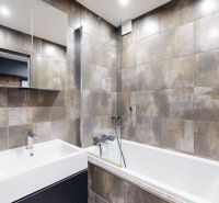 Koupelna s moderním obkladem a sanitou ve 4-pokojovém bytě.