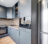 Kuchyně ve 4-pokojovém bytě s moderním vybavením a podlahou s dřevěným dekorem.
