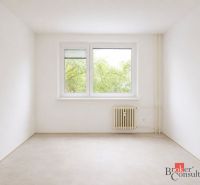 Světlý pokoj se stromy za oknem, radiátorem a podlahou s dřevěným dekorem ve 4pokojovém bytě.