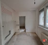 Místnost v 4-pokojovém bytě s bílými stěnami a velkým oknem.