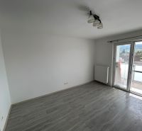 Pokoj s podlahou s dřevěným dekorem a balkonem ve 3-pokojovém bytě.