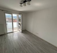 Pokoj v 3-pokojovém bytě s podlahou s dřevěným dekorem a balkonem.