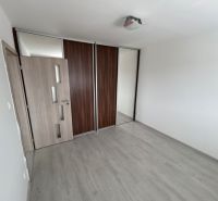 Prázdný pokoj v 3-pokojovém bytě s podlahou s dřevěným dekorem a vestavěnou skříní.