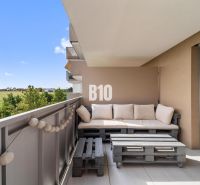 Balkon ve 4-pokojovém bytě s výhledem na okolí Nitry a dřevěným posezením z palet.