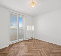 Prázdný pokoj s podlahou s dřevěným dekorem a balkónovými dveřmi ve 3-pokojovém bytě.