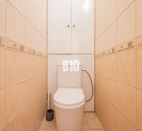 Toaleta s béžovým obkladem v 1-pokojovém bytě, praktický design a úložný prostor.
