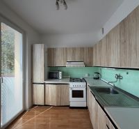 Kuchyně v 3-pokojovém bytě s podlahou s dřevěným dekorem a přímým vstupem na balkon.