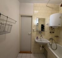 Koupelna v 3-pokojovém bytě s umyvadlem, vanou a ohřívačem vody na stěně.