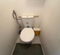 Toaleta 3-pokojového bytu s bílými stěnami a dlaždicemi.