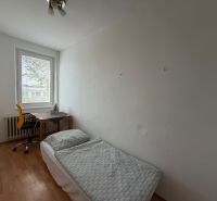 Pokoj v 3-pokojovém bytě s postelí, stolem a podlahou s dřevěným dekorem.