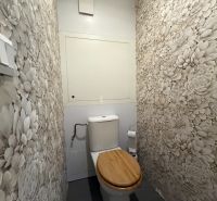Toaleta s květinovými tapetami a dřevěným sedátkem ve 3-pokojovém bytě.