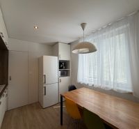 Kuchyně s bílou lednicí, barevnými židlemi a podlahou s dřevěným dekorem v 3-pokojovém bytě.