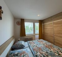 Ložnice s velkou skříní, manželskou postelí a oknem v 3-pokojovém bytě.