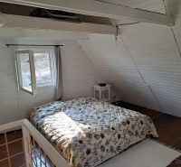 Ložnice s podlahou s dřevěným dekorem a postelí v chatě.