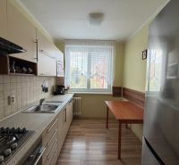Kuchyně ve 3-pokojovém bytě s podlahou s dřevěným dekorem a kuchyňskou linkou.