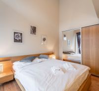 Ložnice s postelí a podlahou s dřevěným dekorem v rekreačním apartmánu.