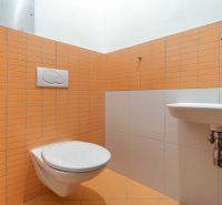 Koupelna v Rekreačním apartmánu s oranžovými obklady a závěsnou toaletou.