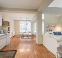 Rekreační apartmán s podlahou s dřevěným dekorem, kuchyní, jídelním stolem a pohodlným sezením.