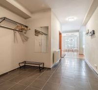 Chodba rekreačního apartmánu s dlažbou, zrcadlem a věšákovou stěnou.