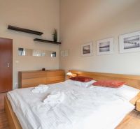 Světlá ložnice v rekreačním apartmánu s podlahou s dřevěným dekorem a jednoduchým zařízením.