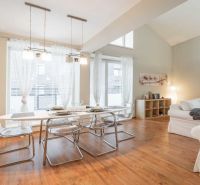 Rekreační apartmán s jídelním stolem, pohodlnými sedačkami a podlahou s dřevěným dekorem.