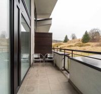 Balkón rekreačního apartmánu na Donovalech s výhledem na přírodu a chaty.