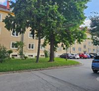 Parkoviště u 3pokojových bytů na Studentské ulici v Trnavě, obklopené zelení a stromy.