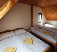 Podkrovní pokoj na chatě s pěti postelemi a dřevěným stropem.