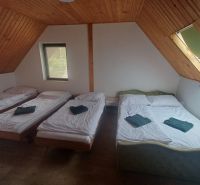 Ložnice v chatě se třemi postelemi a podlahou s dřevěným dekorem.