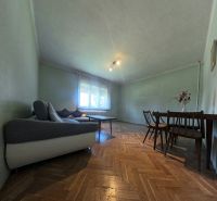 Obývací pokoj v rodinném domě s pohovkou, stolem a podlahou s dřevěným dekorem.