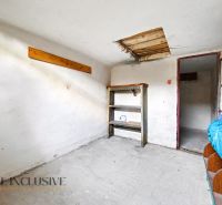 Minimalistická místnost s regály v 3-pokojovém bytě, betonová podlaha, neutrální interiér.