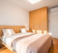 Ložnice s manželskou postelí, skříní a podlahou s dřevěným dekorem v 2-pokojovém bytě.