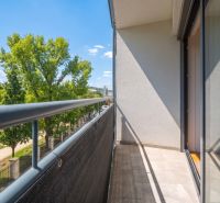 Balkon 2pokojového bytu s výhledem na zeleň a modrou oblohu.